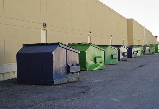 a construction worker empties a wheelbarrow of waste into the dumpster in Durant